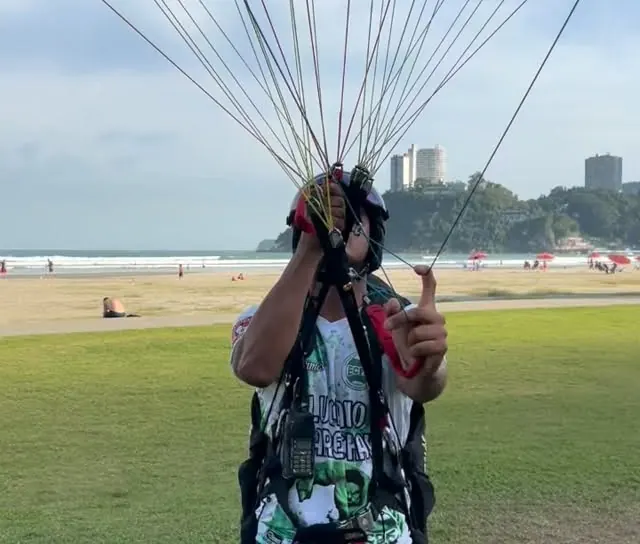 Aluno segurando os tirantes, com as linhas da vela abertas acima dele