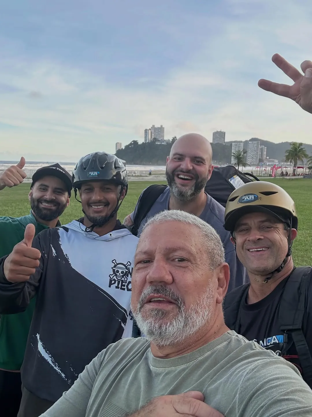 Xandão com alunos de capacete fazendo joinha na praia