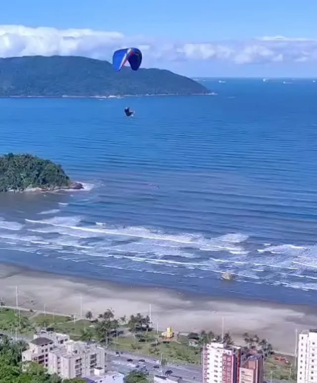 Vista do alto do Morro do Itararé: o mar, a ilha e um parapente voando sobre a praia